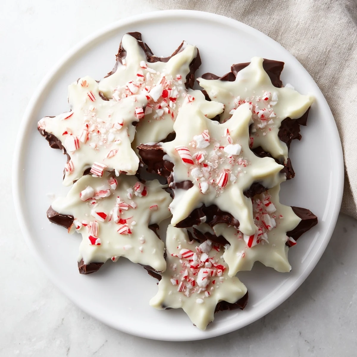 Rich, dark, and white chocolate layers with crushed peppermint form these delicious Peppermint Bark Snowflakes.