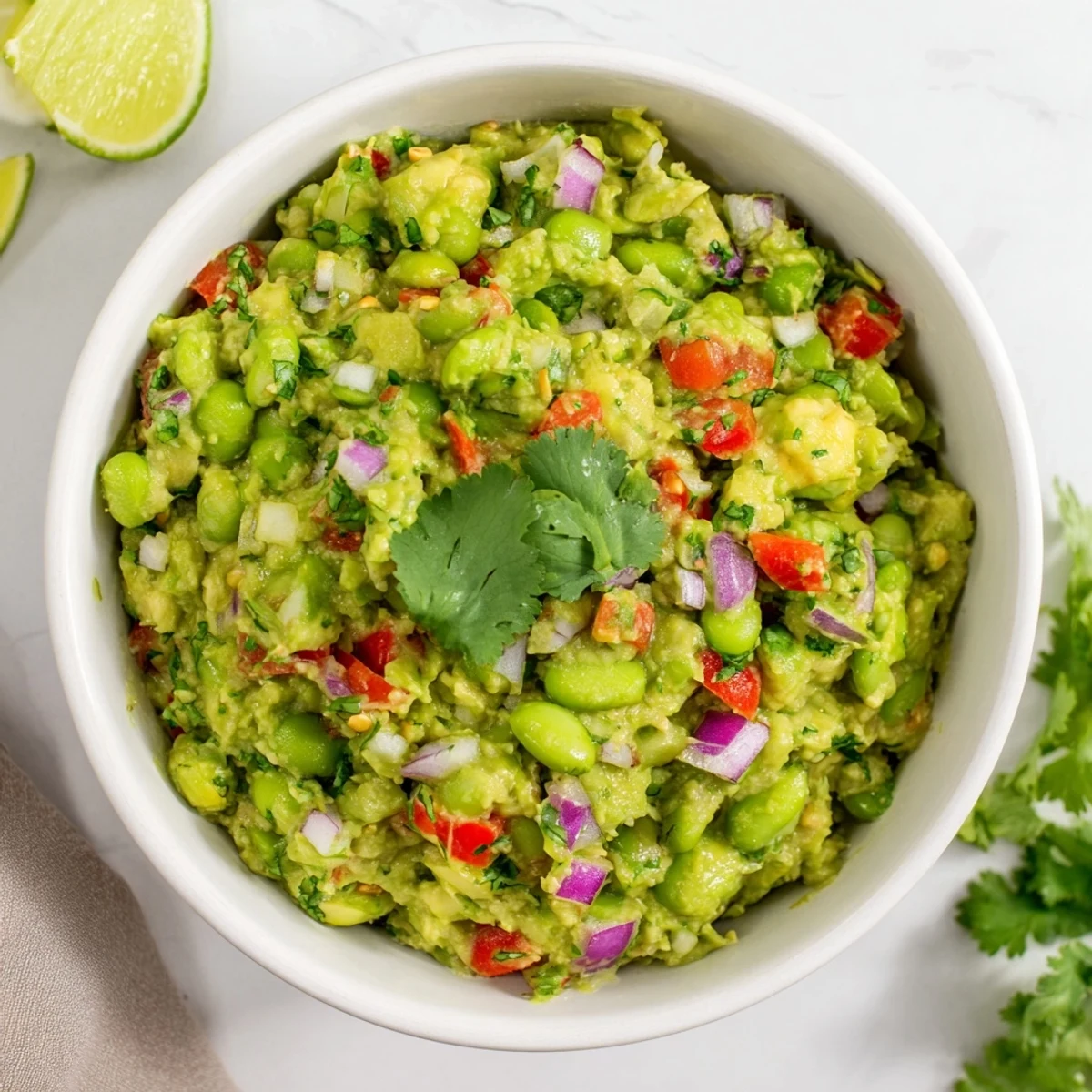 Creamy edamame guacamole, a vibrant green dip with visible chunks, ready to be served with chips.