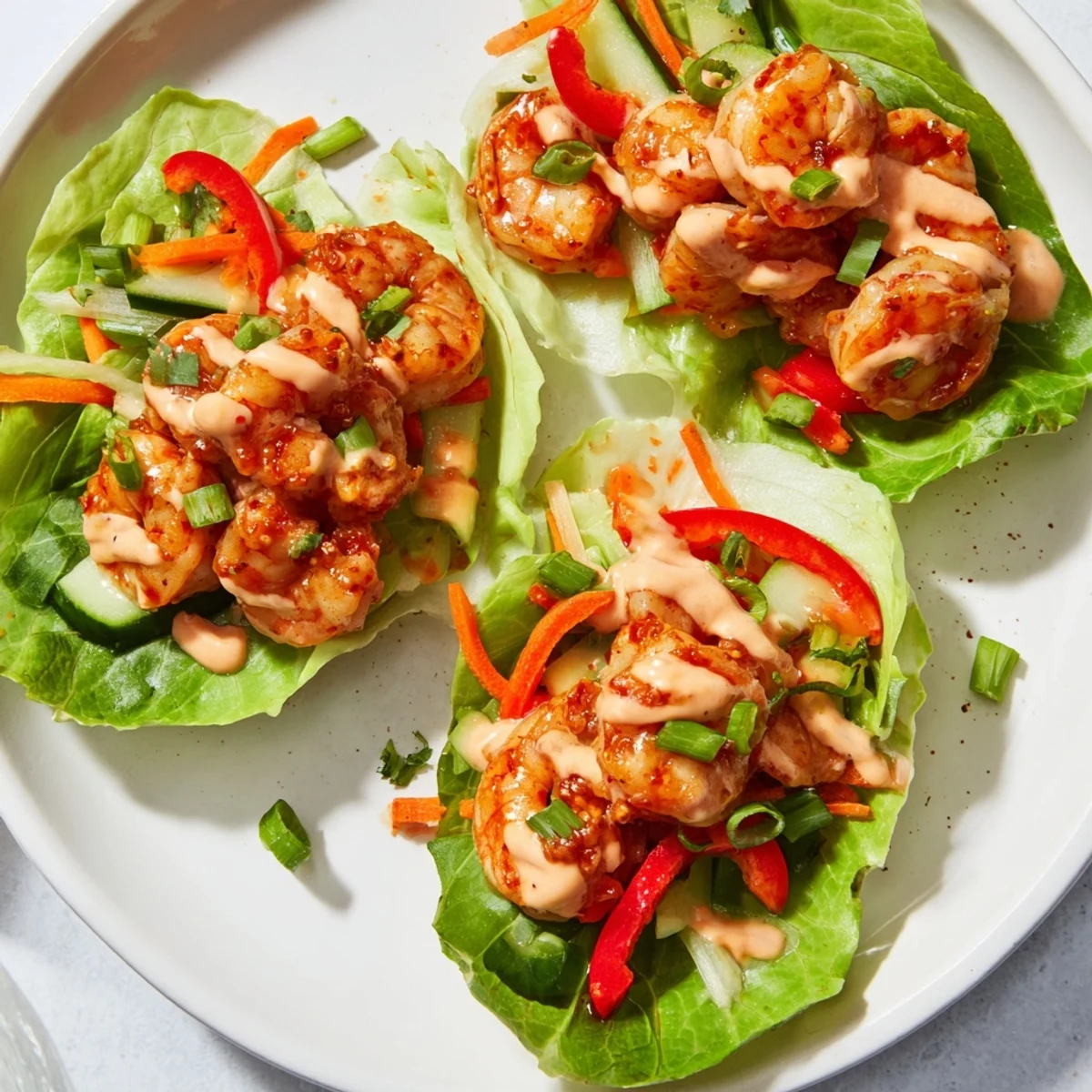 Golden-seared shrimp lettuce cups overflowing with colorful vegetables and a creamy, flavorful sauce.