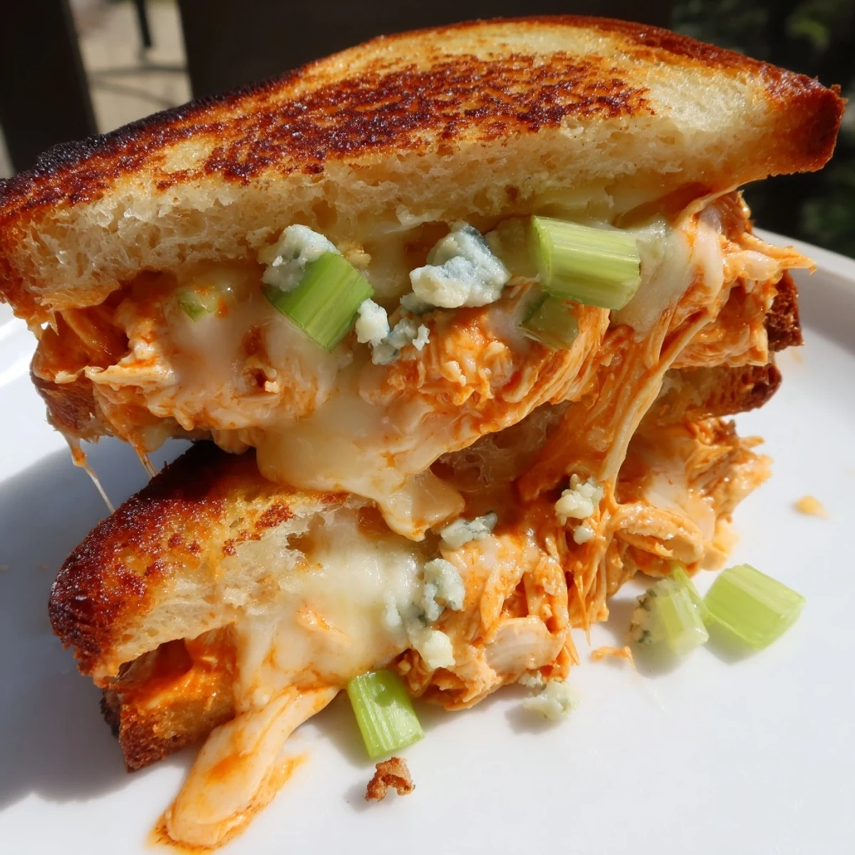 A close-up of a perfectly grilled Buffalo Chicken Grilled Cheese, with toasted bread and gooey cheese pull.