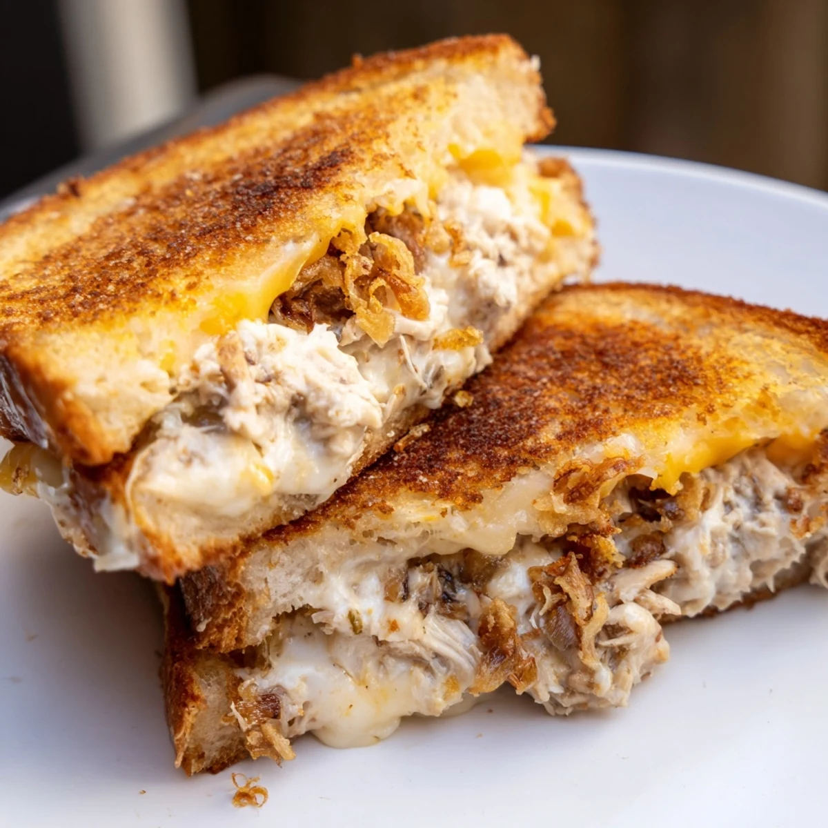 A close-up of a perfectly grilled Crispy Shallot Chicken Grilled Cheese, ready to be sliced and enjoyed.