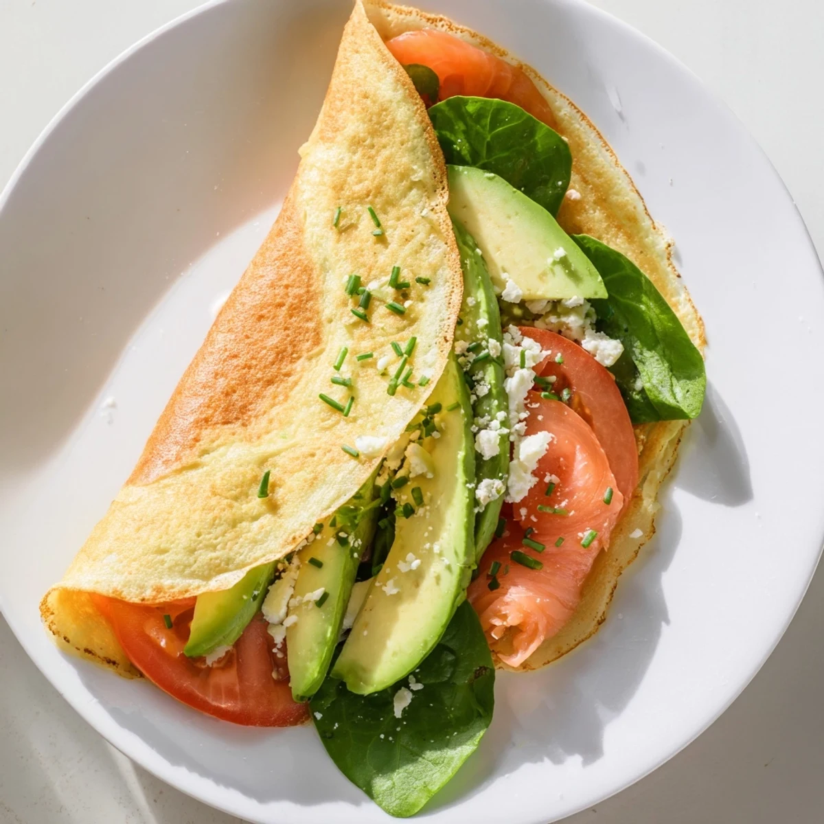 Fluffy blender egg crepe wrap, rolled up and showing juicy fillings like tomato and avocado.