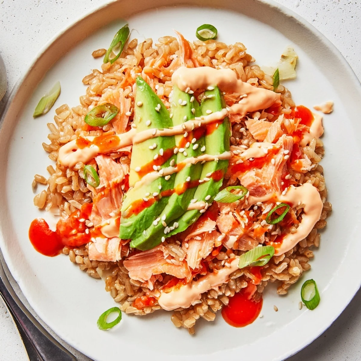 Microwaved Emily Mariko Salmon Rice Bowl with seasoned rice, flaked salmon, avocado, green onions, sesame seeds, and crispy nori sheets on the side.