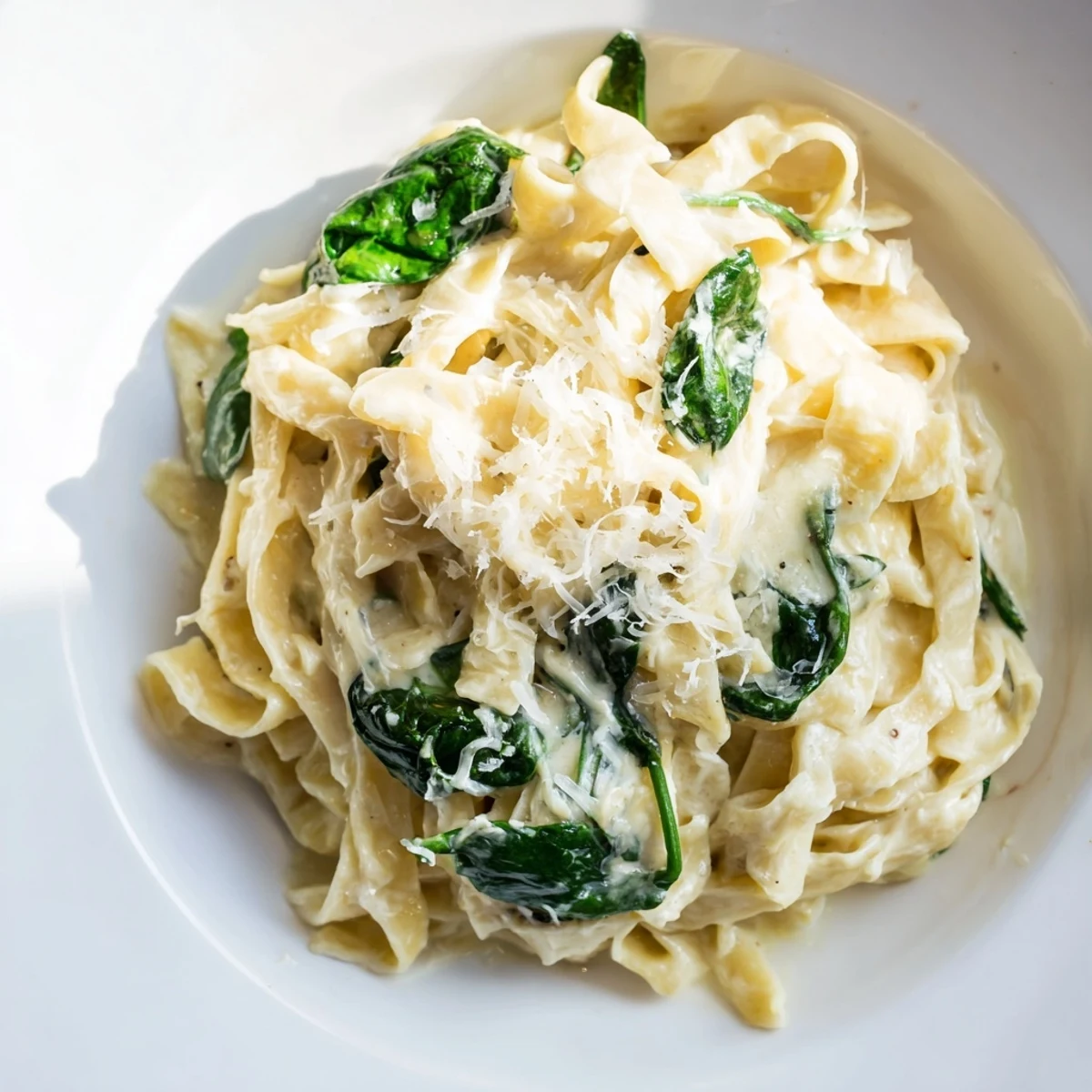 Close-up of Creamy Garlic Spinach Pasta, highlighting tender noodles and vibrant green spinach leaves, perfect for a comforting weeknight vegetarian dinner.