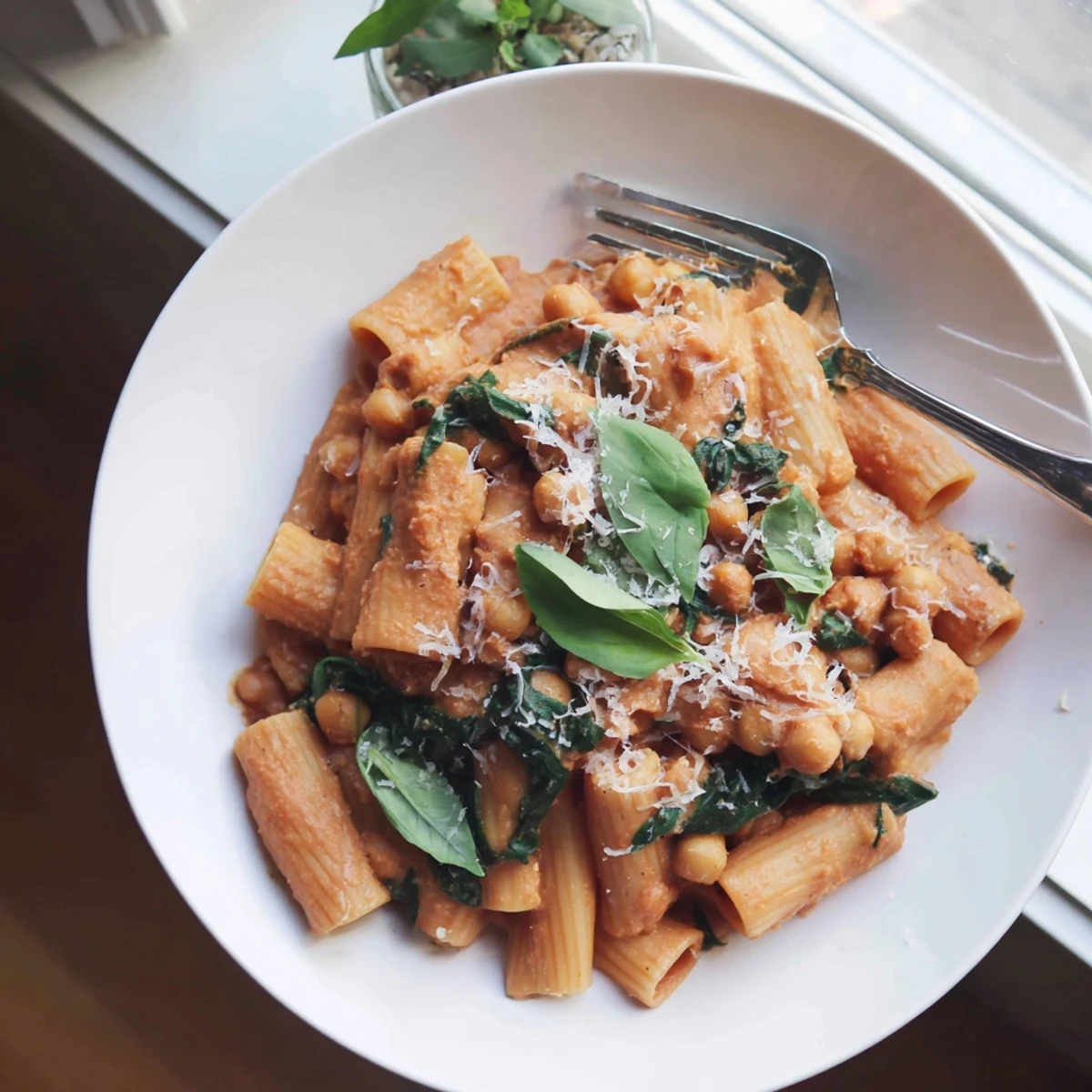 Creamy Tuscan Chickpea Pasta served in a white bowl with fresh basil and grated Parmesan, a hearty vegetarian main dish.