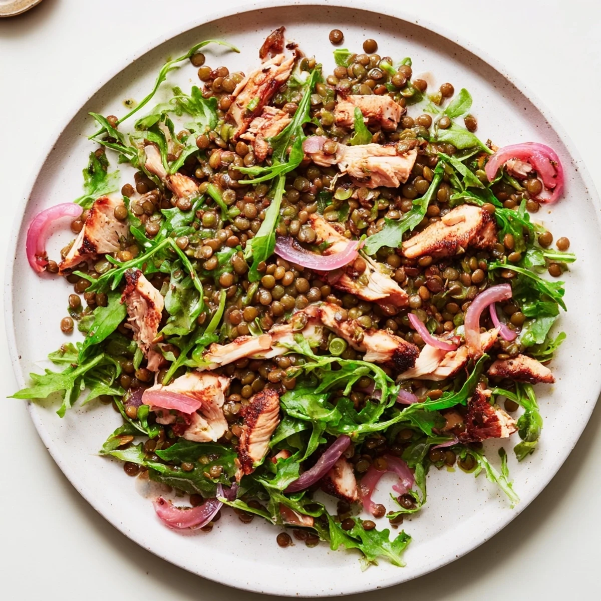 A protein-packed Lentil & Chicken Spring Salad featuring pickled onions, cherry tomatoes, and a tangy Dijon vinaigrette on a bed of fresh arugula.