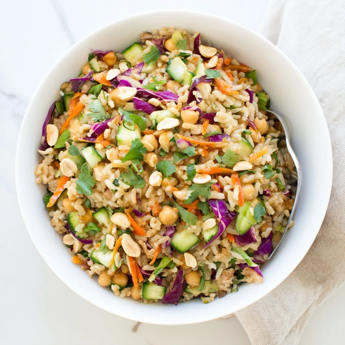 A vibrant Peanut Chickpea Rice Bowl topped with crunchy peanuts and colorful shredded vegetables.  