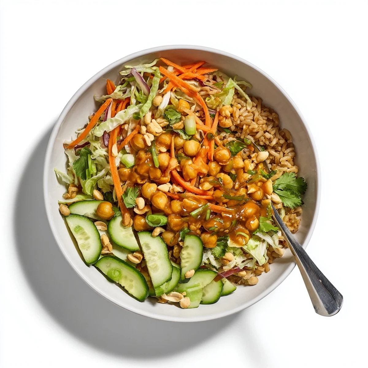 Close-up of a Peanut Chickpea Rice Bowl with carrots, cabbage, cucumber, and roasted peanuts.
