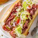 A close-up of the hearty Italian grinder sandwich, featuring chopped meats and melted provolone on a toasted roll.  