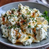 High-protein cottage cheese scrambled eggs, gently cooked to creamy perfection, garnished with green onions and cracked black pepper.  