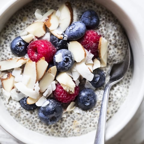Creamy poppy seed chia pudding layered with fresh berries and toasted almonds in a clear glass jar.  