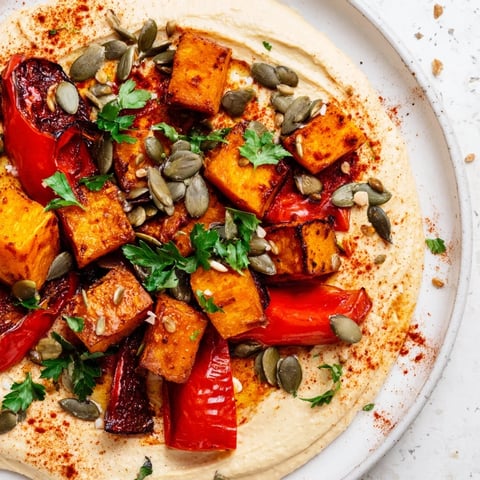 Creamy butter bean hummus topped with golden roasted butternut squash, sweet potatoes, and red bell peppers, garnished with toasted seeds and fresh parsley.  