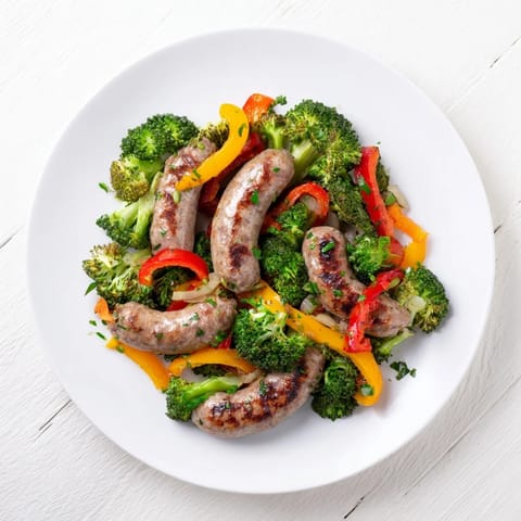 A simple rustic sheet-pan sausage recipe displaying sizzling sausage links nestled amid colorful bell peppers.