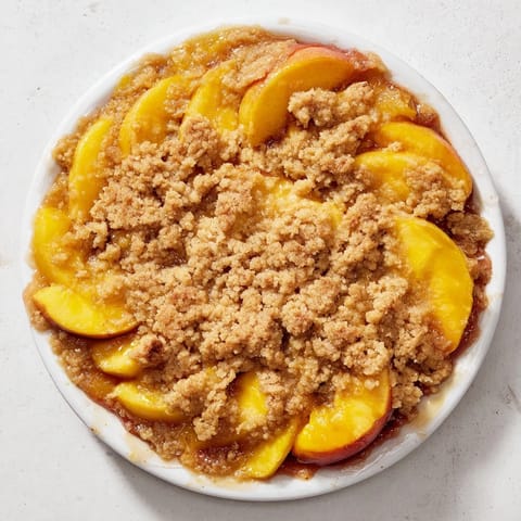 A close-up of a freshly baked Peach and Ginger Crumble, showing the delicious, fruity filling.