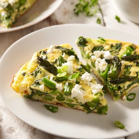 A close-up of a perfectly baked Frittata with Spring Greens, featuring creamy goat cheese and vibrant colors.