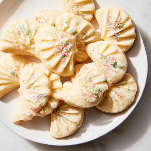 Buttery, festive Spritz Cookies in a layered fan formation, showing off the perfectly baked edges of the cookies.