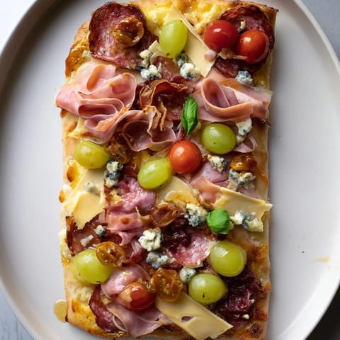 Savory Rustic Raft appetizer, loaded with sliced salami, prosciutto, and cheeses atop golden flatbread.
