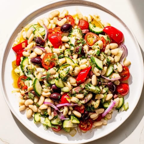 A hearty, chilled dense bean salad with prosciutto, showcasing fresh herbs and a zesty dressing.