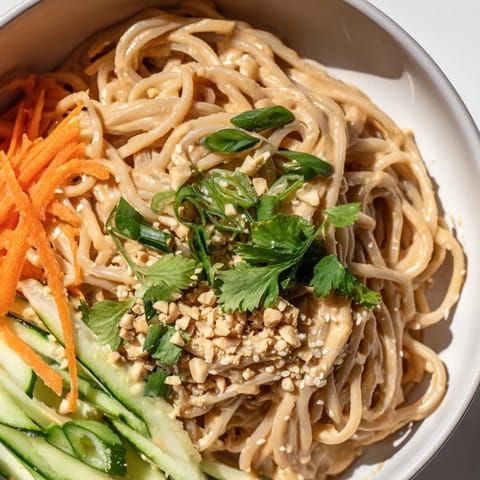 Creamy cold sesame noodles with fresh herbs, a delightful vegetarian Asian-inspired meal ready to eat.