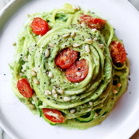 Green zoodles tossed in velvety avocado pesto, garnished with juicy red cherry tomatoes and fresh basil.