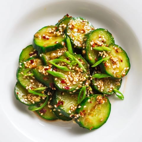 A vibrant bowl of Shake Shake Garlic Cucumbers garnished with green onions and sesame seeds, ready for a quick side dish.