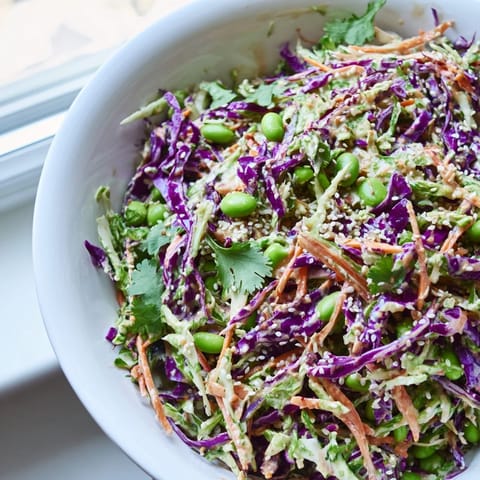 In a bright bowl, the Crunchy Thai Peanut Salad is topped with chopped peanuts and fresh cilantro.