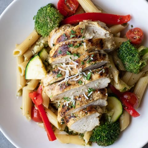 A vibrant pan of Garlic Herb Chicken & Veg Pasta garnished with parsley, lemon zest, and Parmesan.
