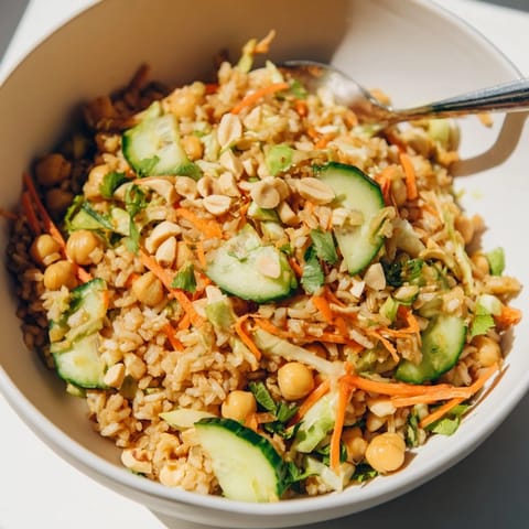 Steamed brown rice and chickpeas in a bowl, drizzled with creamy peanut dressing and fresh cilantro.  