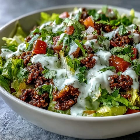 Freshly seasoned ground beef and vibrant toppings fill a bowl of crisp romaine lettuce for this Healthy Taco Bowl.