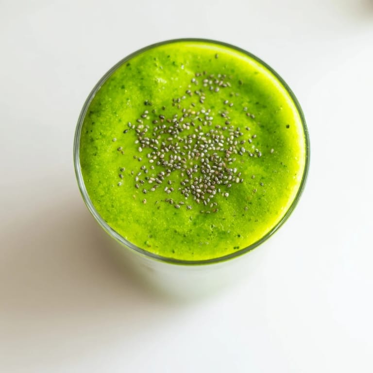 A close-up of a blender pitcher filled with creamy Green Detox Smoothie, showcasing its vivid green color from spinach and romaine.