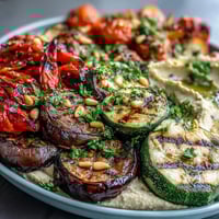 Grilled Veggie Platter with Hummus - colorful grilled vegetables arranged around creamy homemade hummus, garnished with parsley and pine nuts.  