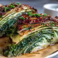 Golden roasted cabbage steaks seasoned with garlic, smoked paprika, and lemon zest for a vibrant vegan side dish.  
