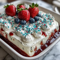 Memorial Day Red White Blue Poke Cake with vibrant red and blue gelatin swirls in a fluffy white cake, topped with creamy whipped topping and patriotic sprinkles.